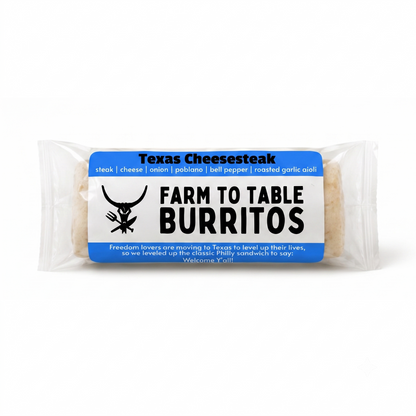 A packaged burrito on a clean white background. The clear plastic wrapper shows a round burrito with a blue and white paper label that reads 'Texas Cheesesteak' and 'FARM TO TABLE BURITOS' with a black steer logo.
